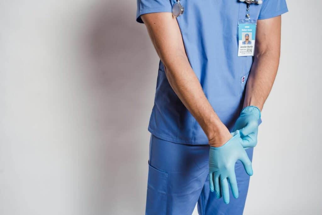 Male doctor putting on sterile gloves